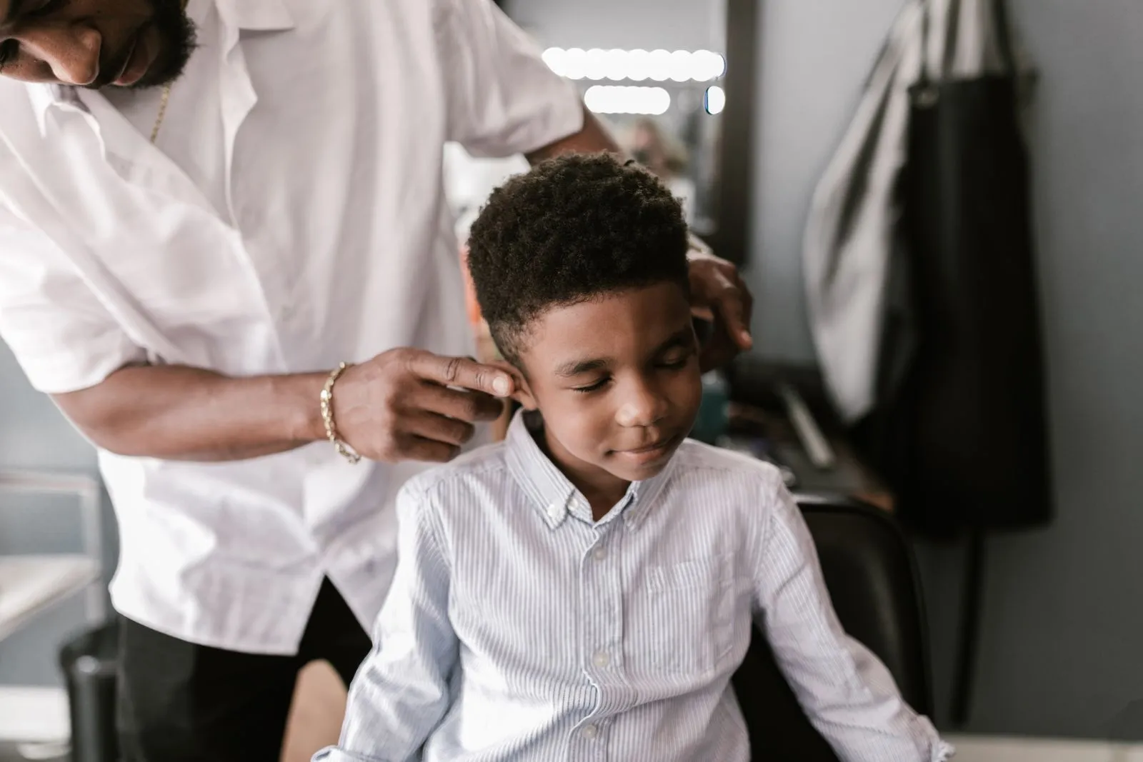 A young boy receiving a haircut from a barber in a salon setting.
